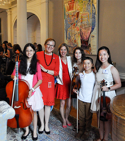 The First Lady and Secretary of Education Aimee Guidera stand with a group of homeschool students holding musical instruments.