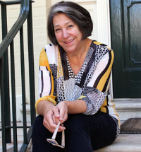 Georgia Esposito, Mansion Director, sits on the steps with a black railing to her left.