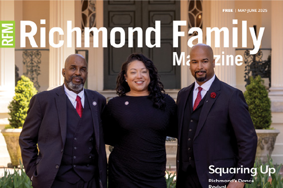 An older man, young woman and young man stand stand in front of a federal style mansion. The men are wearing three piece suits with red ties and the women is wearing a black dress.