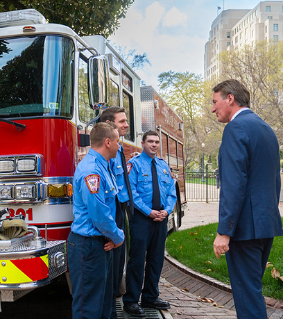 three firemen and the Governor standing in front of a fire truck