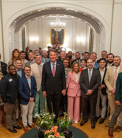 Governor and First Lady pose with a group in the ballroom of the Executive Mansion.