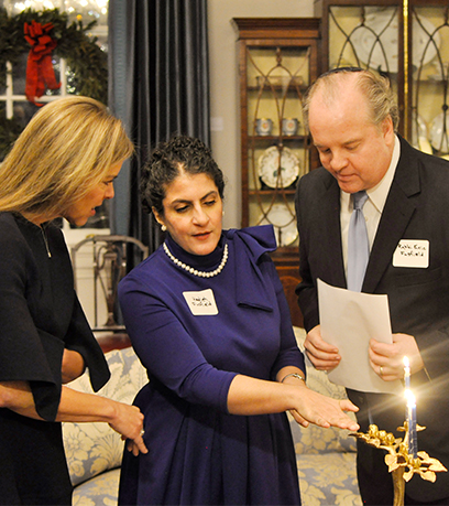 First Lady Suzanne Youngkin, a woman and a man wearing a yarmulke stand in front of a menorah.