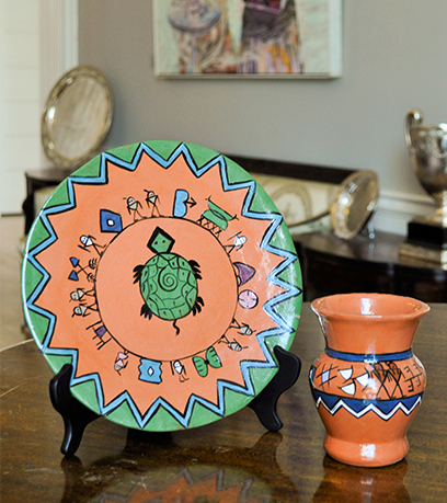 A terracotta plate and vase with Native American symbolism.