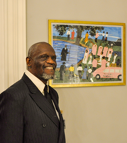 An artist stands next to his colorful painting.