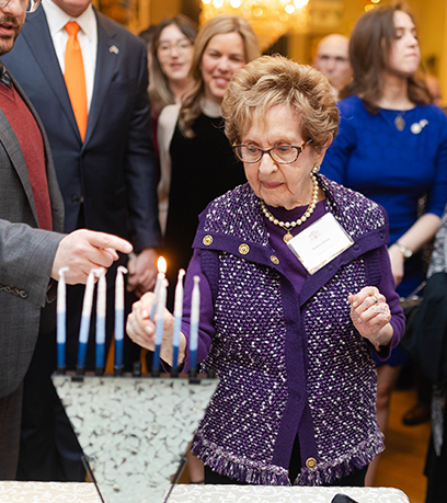 Holocaust survivor Halina Zimm uses a candle to light a menorah.