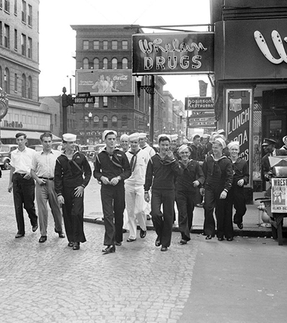 Black and white photograph of 1940s era Navy sailors walking on a city street in Norfolk, Virginia.