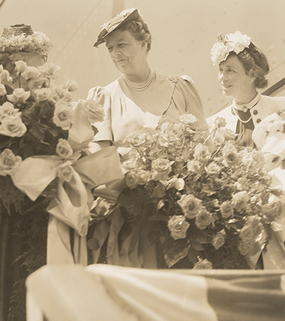 A black and white photo of three ladies holding flowers.