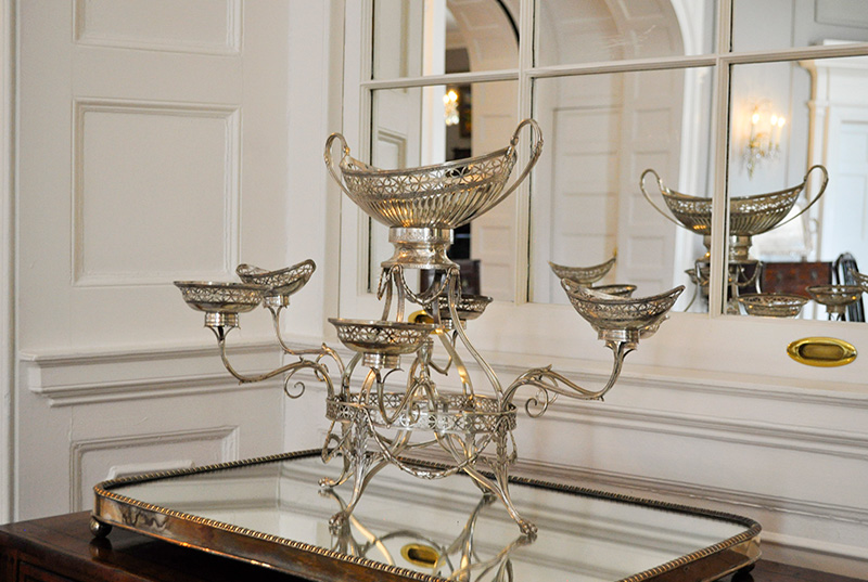 Silver apern rests on a mirrored tray in front of a mirror with panels.